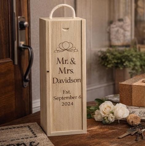 Wooden wine box with engraved text 'Mr. & Mrs. Davidson Est. September 6 2024' on a wooden surface.