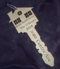 Decorative key-shaped ornament with engraved text on a purple fabric background